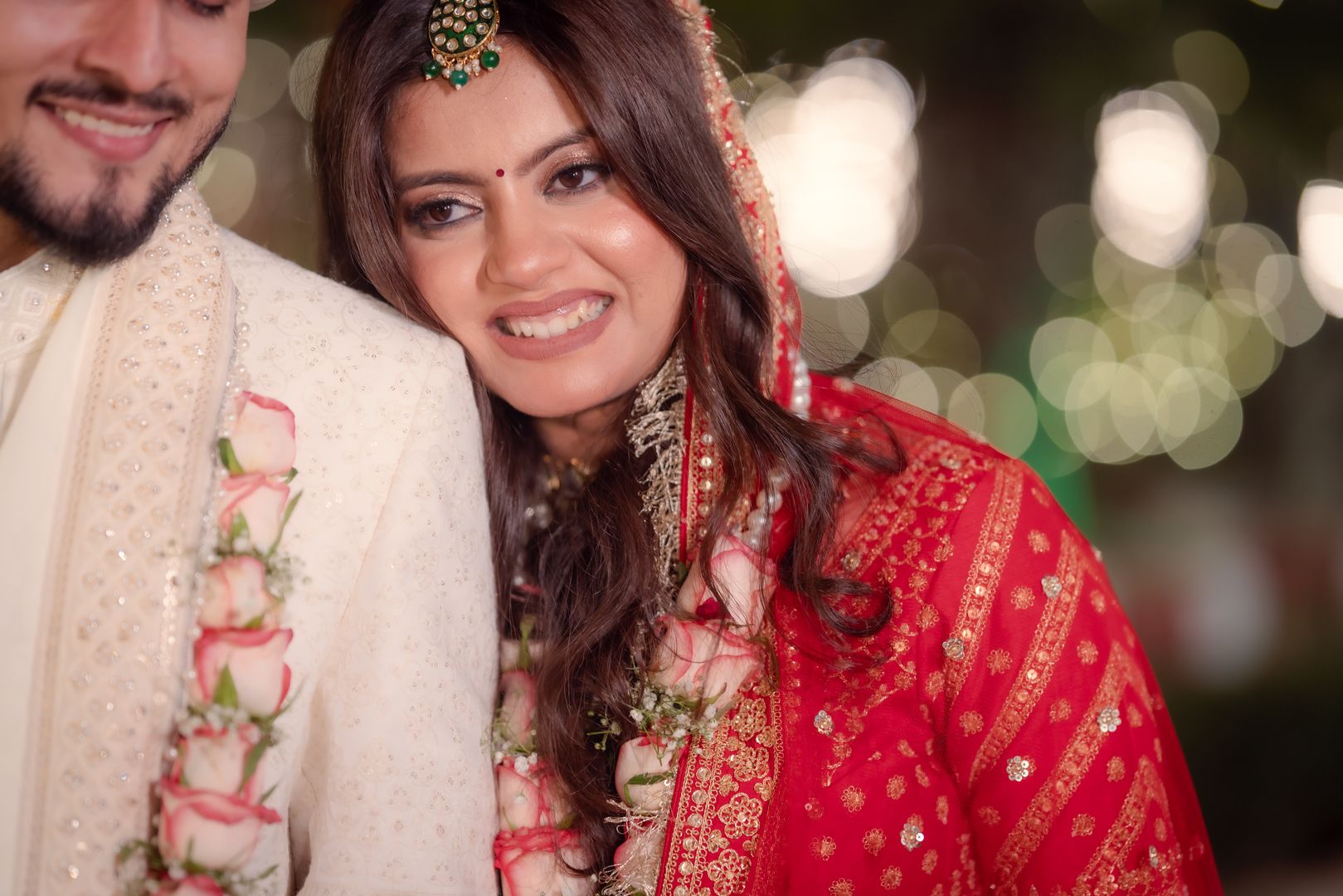 Bride smiling with rose garland, photographed by Mograa House