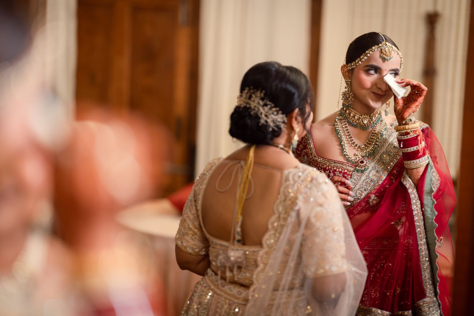 Bride wiping a happy tear while her mother looks on, photographed by Mograa House
